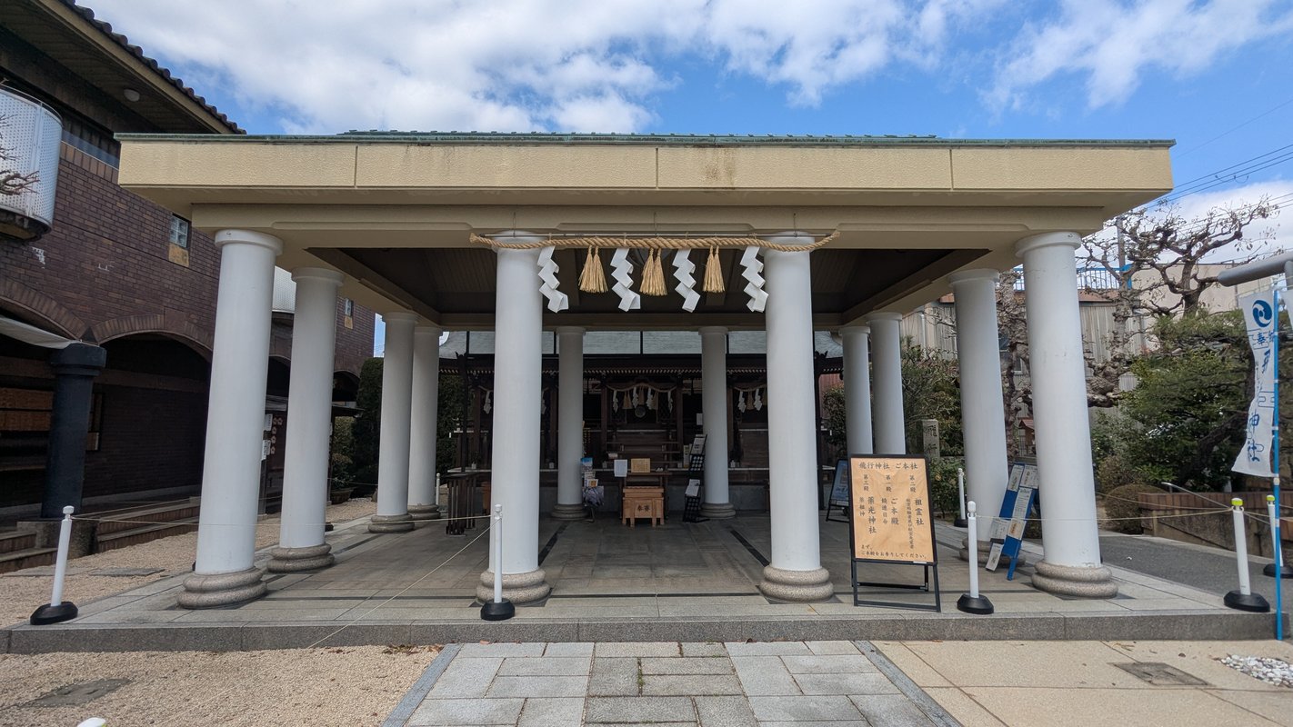 這幅圖展示了八幡市的飛行神社，周圍樹木蔥鬱，環境寧靜。